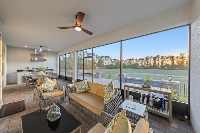sunroom featuring ceiling fan, outdoor lounge area, exterior kitchen, and outdoor dining space