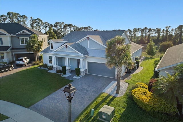 view of front of house featuring stone siding, a garage, a front yard, decorative driveway, and covered porch