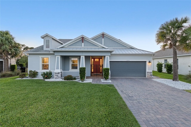 view of front of home featuring an attached garage, stucco siding, a front yard, decorative driveway, and covered porch