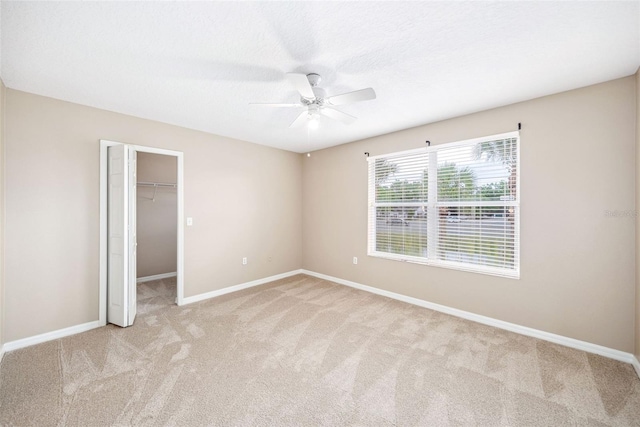 5004 Ashford Falls Ln, Oviedo, FL 32765 - unfurnished bedroom with light carpet, baseboards, a spacious closet, a closet, and a ceiling fan