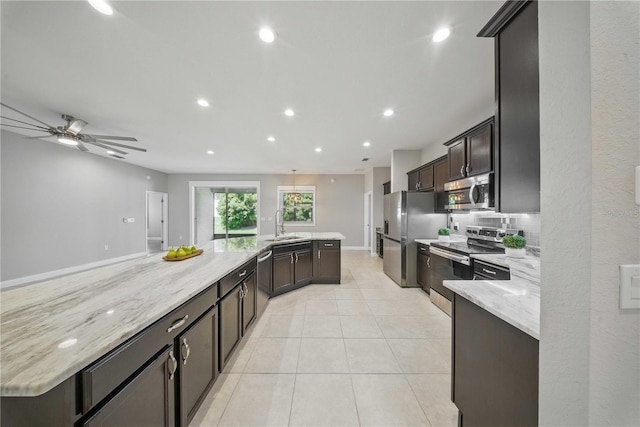 5829 Valentino Way, Lakeland, FL 33812 - kitchen featuring a large island with sink, a sink, light stone counters, stainless steel appliances, and recessed lighting