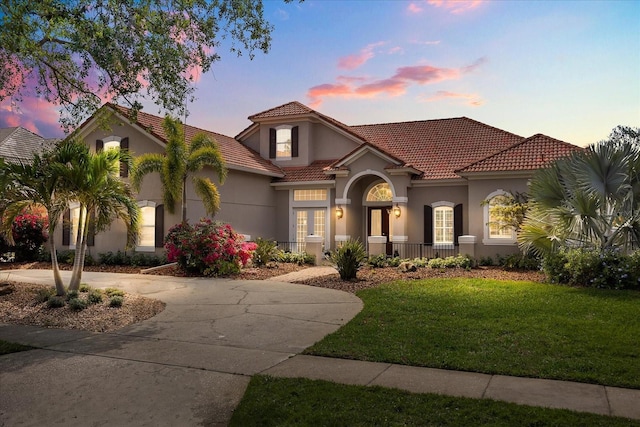 10664 Emerald Chase Dr, Orlando, FL 32836 - mediterranean / spanish home featuring curved driveway, covered porch, stucco siding, a front yard, and a tile roof