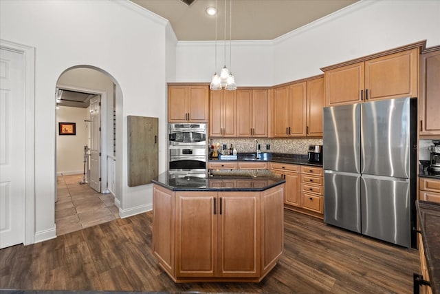 10664 Emerald Chase Dr, Orlando, FL 32836 - kitchen featuring arched walkways, tasteful backsplash, ornamental molding, a kitchen island, and appliances with stainless steel finishes