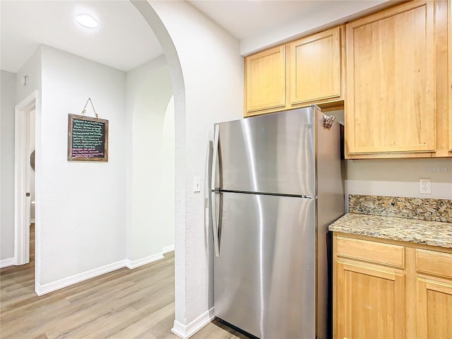 9051 Treasure Trove Ln Unit 405, Kissimmee, FL 34747 - kitchen with freestanding refrigerator, light brown cabinetry, arched walkways, light wood-style flooring, and recessed lighting