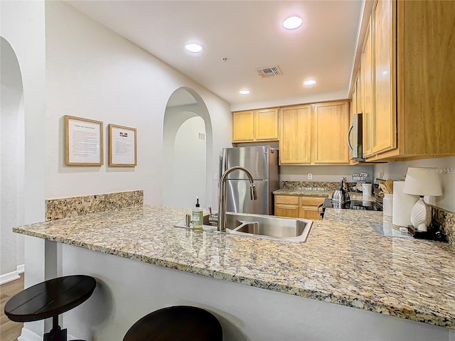 9051 Treasure Trove Ln Unit 405, Kissimmee, FL 34747 - kitchen featuring appliances with stainless steel finishes, a peninsula, light stone countertops, arched walkways, and recessed lighting