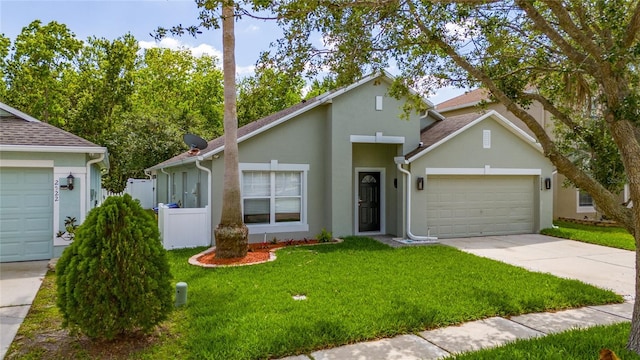 view of front of home featuring stucco siding, fence, a front lawn, an attached garage, and driveway