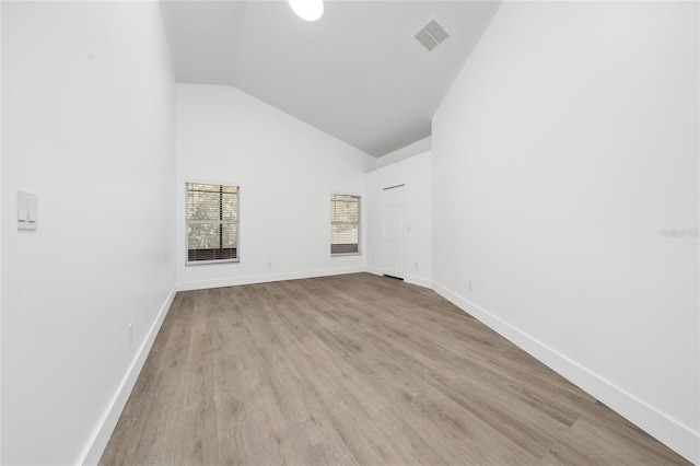 spare room featuring wood finished floors, high vaulted ceiling, baseboards, and visible vents