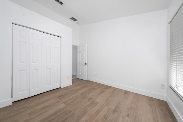 unfurnished bedroom with visible vents, baseboards, and wood finished floors