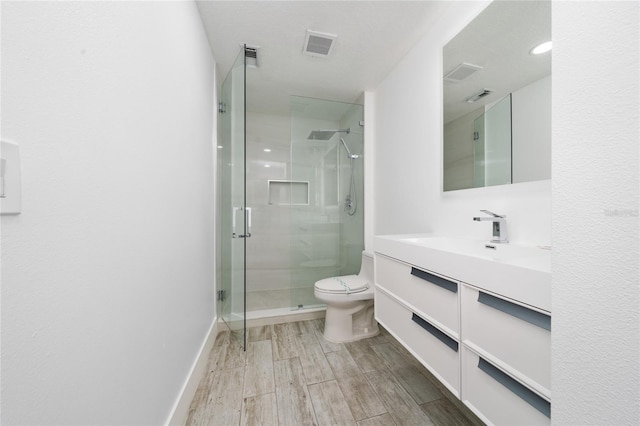 bathroom with baseboards, toilet, a shower stall, vanity, and wood finished floors