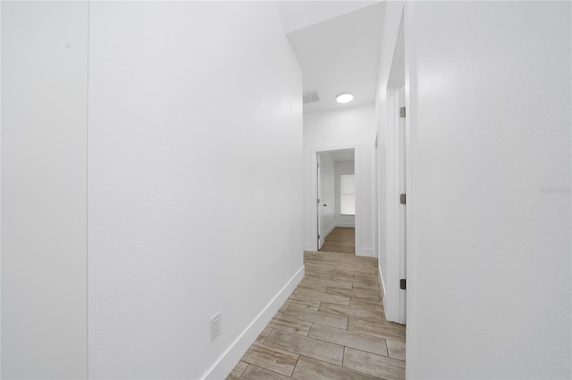 hallway featuring visible vents, baseboards, and wood tiled floor