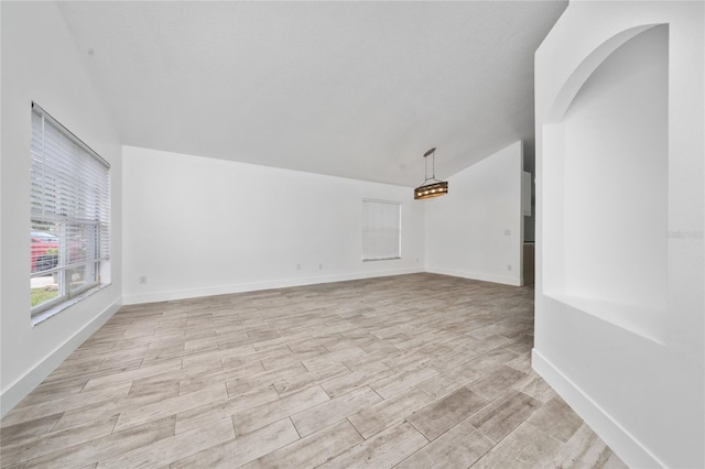 unfurnished room with light wood-style flooring, baseboards, and lofted ceiling