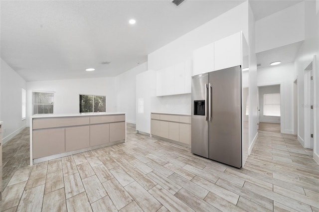 kitchen with stainless steel fridge with ice dispenser, baseboards, white cabinetry, modern cabinets, and wood tiled floor