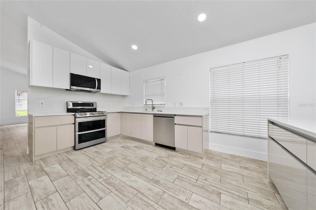 kitchen with white cabinets, recessed lighting, appliances with stainless steel finishes, light countertops, and lofted ceiling