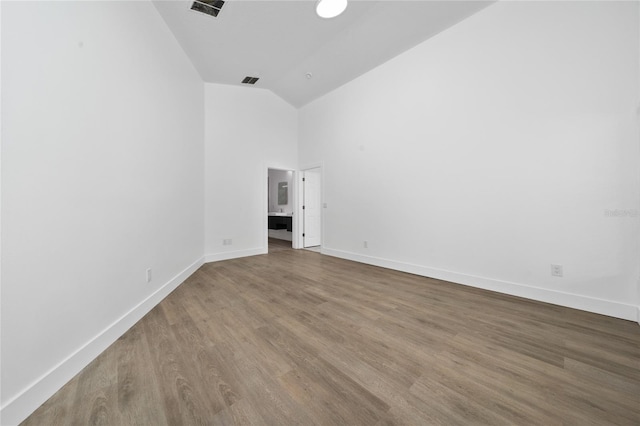 unfurnished room featuring visible vents, baseboards, high vaulted ceiling, and wood finished floors