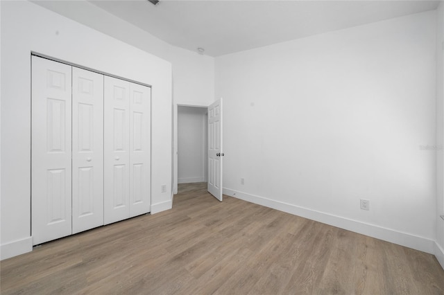 unfurnished bedroom featuring a closet, baseboards, and wood finished floors