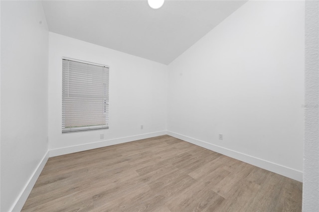 unfurnished room featuring baseboards, wood finished floors, and vaulted ceiling