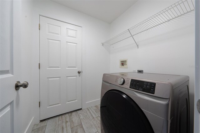 washroom featuring light wood-type flooring, washer / dryer, laundry area, and baseboards