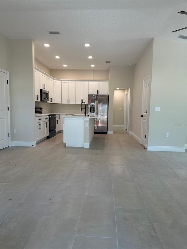 kitchen with recessed lighting, appliances with stainless steel finishes, white cabinets, a sink, and baseboards