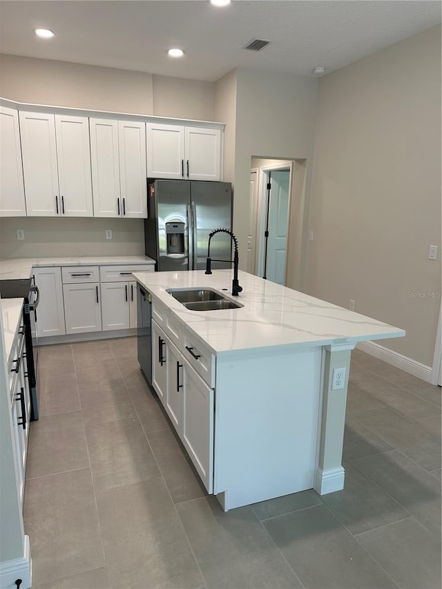 kitchen with light stone counters, a sink, appliances with stainless steel finishes, recessed lighting, and an island with sink