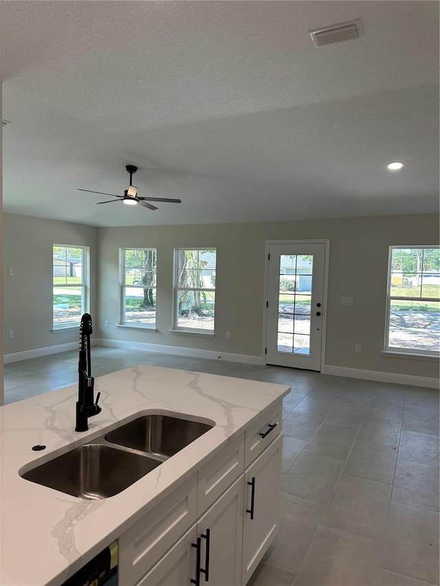 kitchen with open floor plan, visible vents, baseboards, and a sink