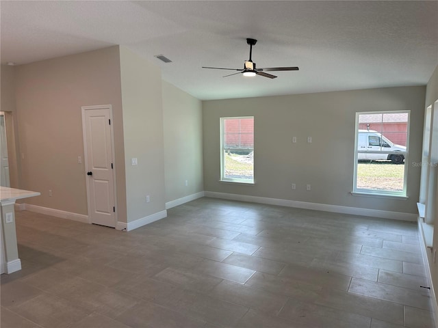 spare room with baseboards, visible vents, and ceiling fan