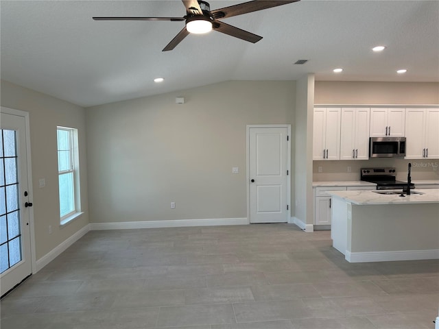 kitchen featuring stainless steel appliances, vaulted ceiling, ceiling fan, a sink, and white cabinetry