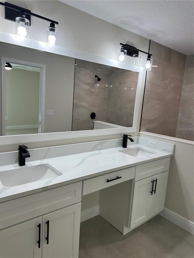 full bathroom with a textured ceiling, double vanity, and a sink