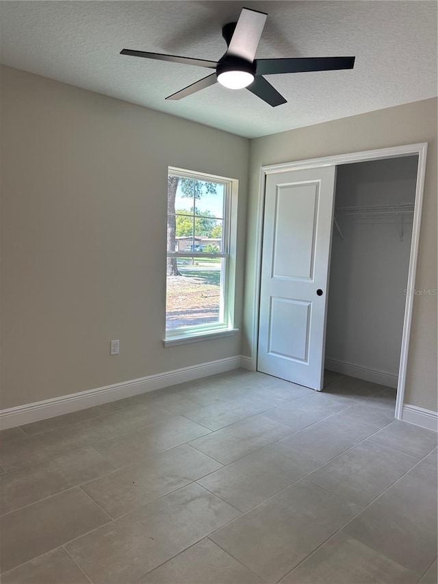 unfurnished bedroom featuring a closet, a ceiling fan, a textured ceiling, and baseboards