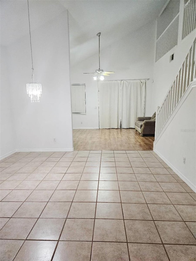 5421 Watervista Dr, Orlando, FL 32821 - unfurnished living room featuring visible vents, light tile patterned flooring, baseboards, high vaulted ceiling, and ceiling fan with notable chandelier