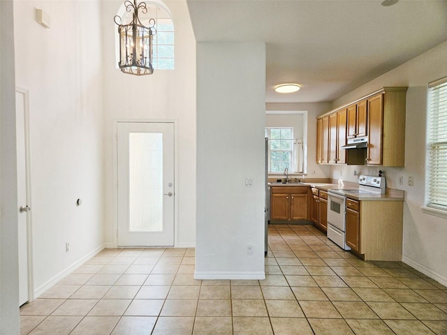 5421 Watervista Dr, Orlando, FL 32821 - kitchen featuring an inviting chandelier, under cabinet range hood, white range with electric stovetop, a sink, and light tile patterned floors