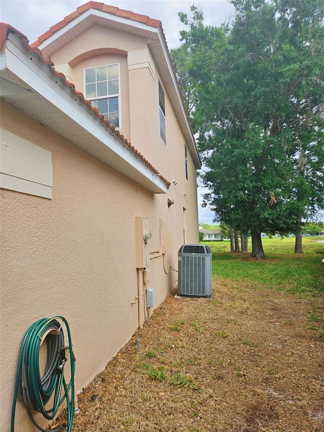 5421 Watervista Dr, Orlando, FL 32821 - view of home's exterior with stucco siding, central air condition unit, and a tiled roof
