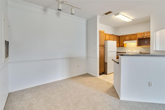 kitchen with freestanding refrigerator, under cabinet range hood, visible vents, stove, and light colored carpet