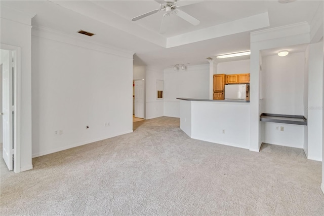 unfurnished living room featuring ornamental molding, a ceiling fan, light colored carpet, and visible vents