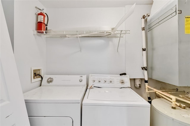 clothes washing area featuring water heater, washing machine and clothes dryer, and laundry area