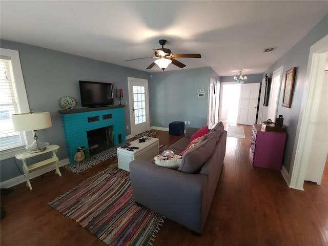 living room featuring a fireplace, visible vents, baseboards, and wood finished floors