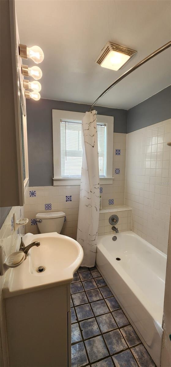 full bath featuring toilet, visible vents, tile walls, and vanity