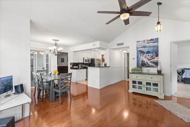 dining area featuring vaulted ceiling, light wood-style flooring, ceiling fan with notable chandelier, and visible vents