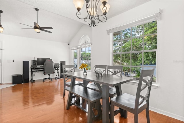 dining room featuring a textured ceiling, vaulted ceiling, wood finished floors, and ceiling fan with notable chandelier