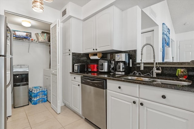 kitchen featuring appliances with stainless steel finishes, light tile patterned floors, a sink, and white cabinetry