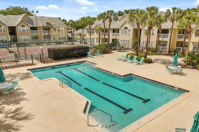 community pool featuring fence, a patio, and a residential view