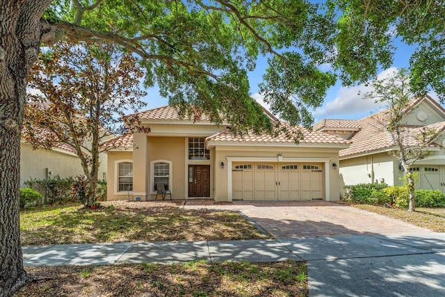 6959 Brescia Way, Orlando, FL 32819 - mediterranean / spanish home featuring an attached garage, a tile roof, stucco siding, and decorative driveway