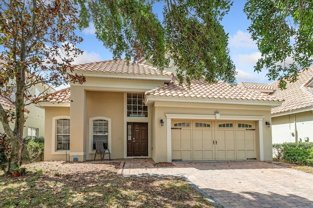 6959 Brescia Way, Orlando, FL 32819 - mediterranean / spanish-style home featuring an attached garage, a tile roof, decorative driveway, and stucco siding