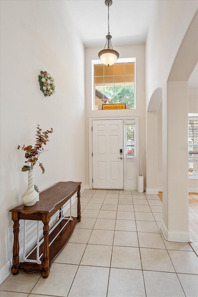 6959 Brescia Way, Orlando, FL 32819 - foyer featuring light tile patterned floors, arched walkways, and plenty of natural light