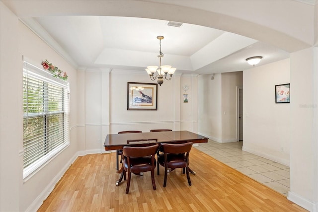 6959 Brescia Way, Orlando, FL 32819 - dining space featuring light wood-type flooring, a tray ceiling, a notable chandelier, and visible vents