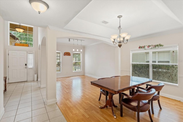 6959 Brescia Way, Orlando, FL 32819 - dining room with arched walkways, baseboards, visible vents, light wood-style floors, and a notable chandelier