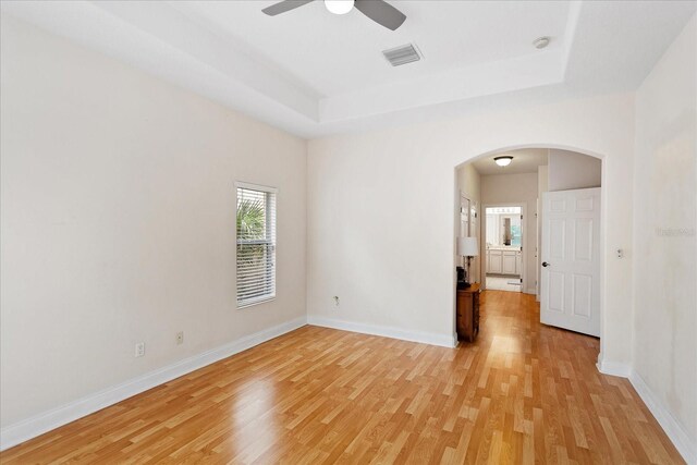 6959 Brescia Way, Orlando, FL 32819 - empty room featuring a ceiling fan, arched walkways, light wood finished floors, baseboards, and visible vents