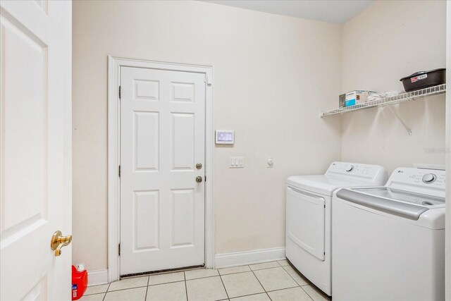 6959 Brescia Way, Orlando, FL 32819 - laundry area with light tile patterned flooring, baseboards, separate washer and dryer, and laundry area