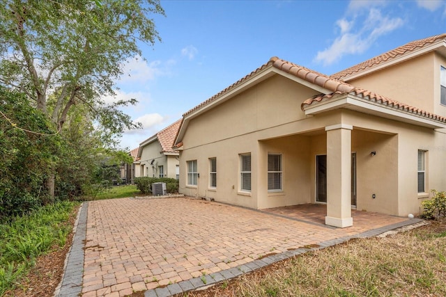 6959 Brescia Way, Orlando, FL 32819 - rear view of house featuring a patio area, a tiled roof, central AC unit, and stucco siding