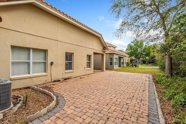 6959 Brescia Way, Orlando, FL 32819 - back of house featuring a patio area, a tiled roof, central AC, and stucco siding