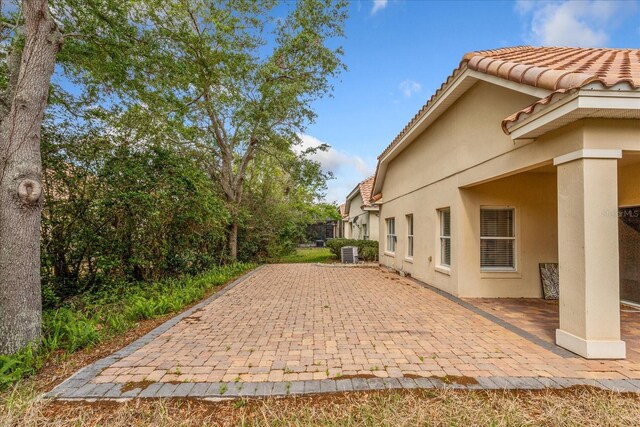 6959 Brescia Way, Orlando, FL 32819 - view of side of property featuring a patio area, a tiled roof, cooling unit, and stucco siding